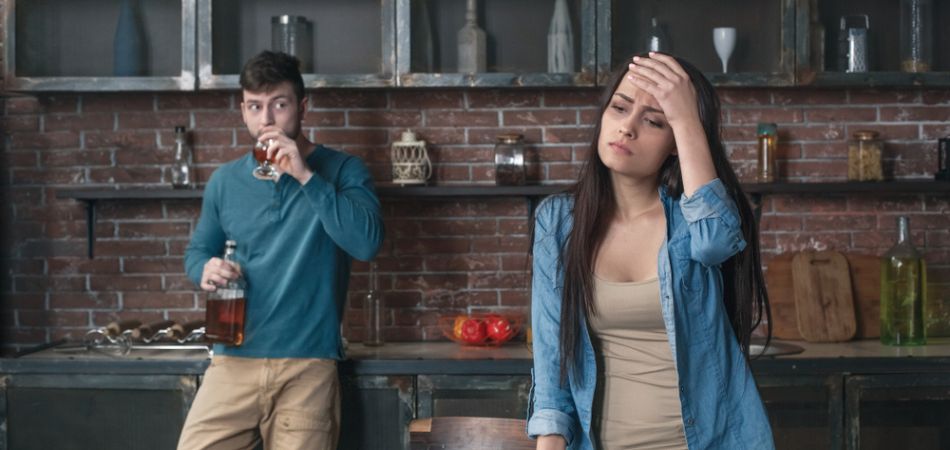 man drinking alcohol infront of wife